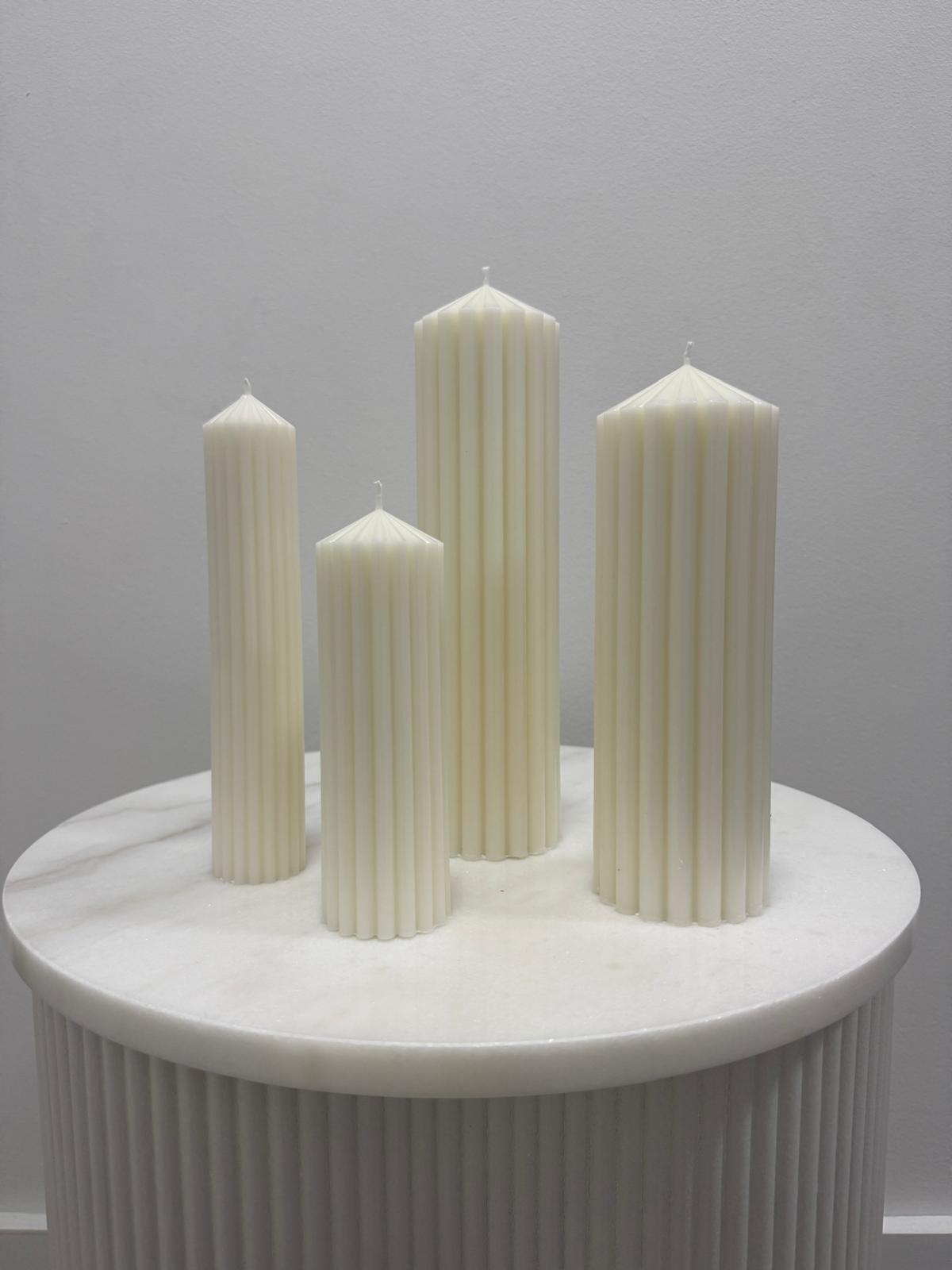 Sculptural pearl-white candles on a marble table